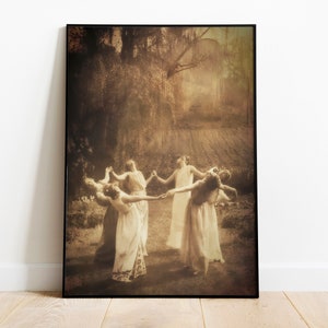 May include: A sepia-toned photograph of five women in long dresses dancing in a circle in a field. The women are holding hands and their dresses are flowing in the wind. The background is a blurry image of trees and a field.