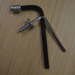May include: A black L-shaped wrench with a silver screw and a silver metal piece attached to the wrench.