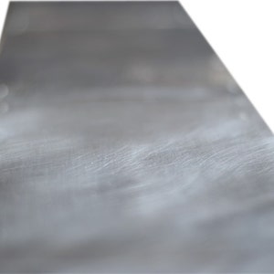 May include: A close-up of a smooth, silver metal surface with subtle scratches and a slight sheen.
