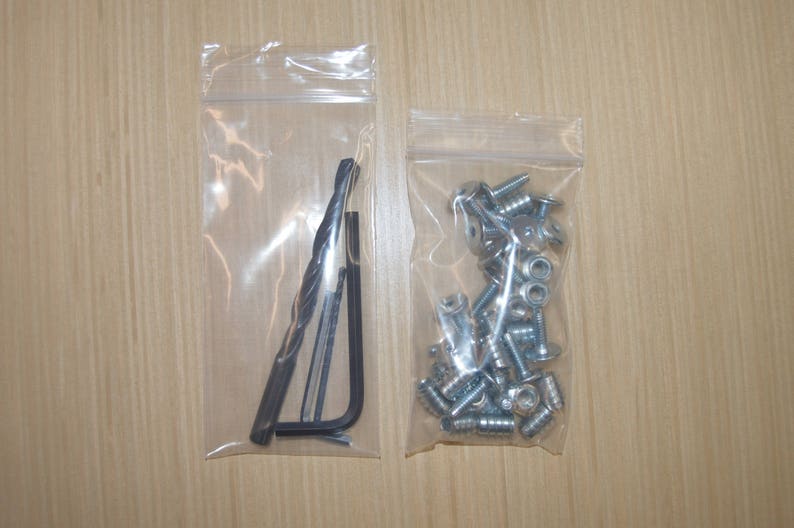 May include: Two clear plastic bags containing hardware. One bag contains a drill bit and a small wrench. The other bag contains a pile of silver screws.