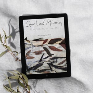 Könnte beinhalten: Ein Tablet-Computer zeigt ein Buchcover mit dem Titel "Gum Leaf Alchemy: Eco-printing on cotton" von Louise Upshall. Das Cover zeigt eine Nahaufnahme eines Stoffes mit einem natürlichen Blattmotiv in Braun-, Rot- und Weißtönen.