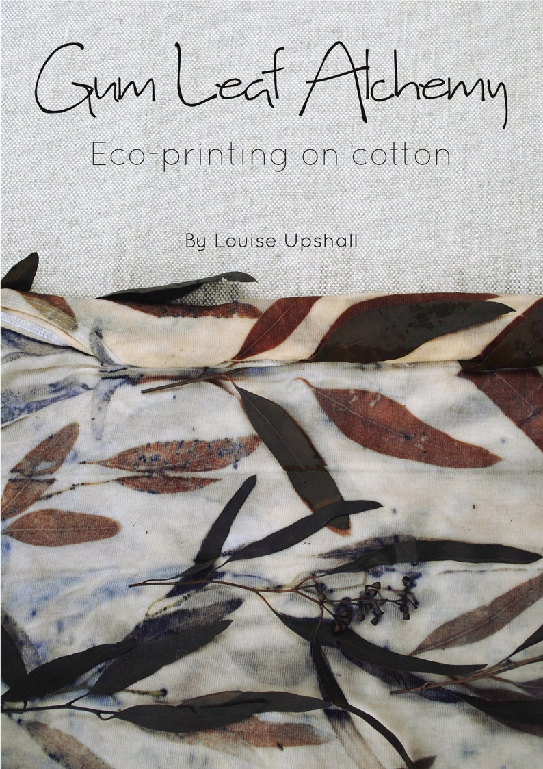 Peut inclure: Un tissu en coton blanc avec des impressions de feuilles brunes et bleues. Le tissu est pli&eacute; en deux et les feuilles sont dispos&eacute;es en motif. Le texte "Gum Leaf Alchemy Eco-printing on cotton By Louise Upshall" est imprim&eacute; sur un fond beige au-dessus du tissu.