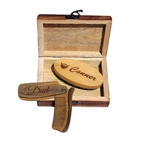 May include: A wooden box containing a wooden comb and a wooden brush. The comb is engraved with the word "Dad" and the brush is engraved with the word "Conner" and a beard icon.