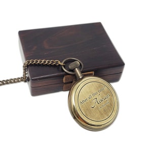 May include: A brass pocket watch with a chain, presented on a dark wooden box. The watch face displays the quote "After all this time? Always" by J.K. Rowling. The watch has a vintage, antique appearance.