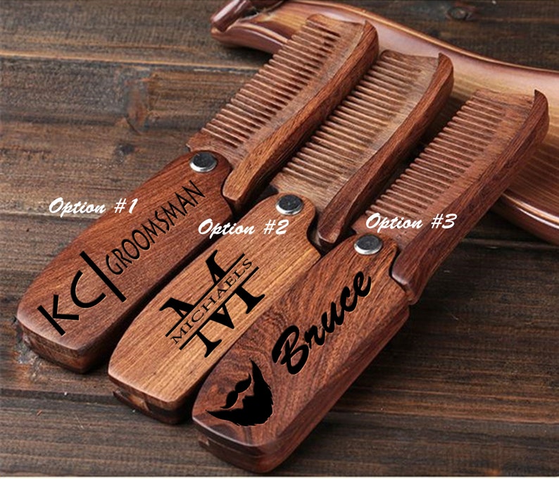 May include: Three wooden pocket combs with personalized engravings. The combs are brown and have a folding design. The engravings include "KC|GROOMSMAN", "MICHAEL", and "Bruce".