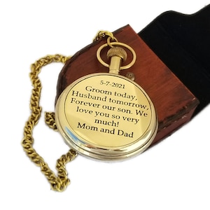 May include: A gold-coloured pocket watch with a chain, presented in a brown leather case. The watch face features engraved text: "Groom today, Husband tomorrow, Forever our son. We love you so very much! Mom and Dad."