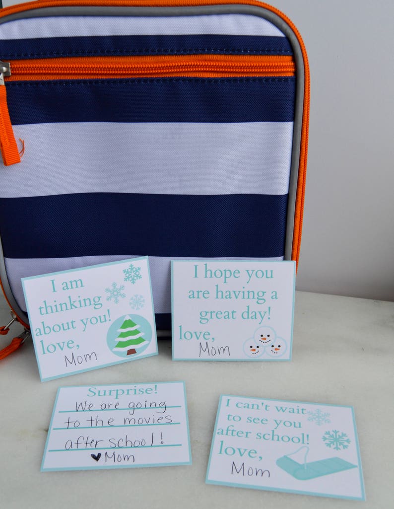 Op de afbeelding: Vier blauwe en witte kaartjes met handgeschreven berichten. De berichten luiden: "Ik denk aan je! Liefs, Mama", "Ik hoop dat je een fijne dag hebt! Liefs, Mama", "Verrassing! We gaan na school naar de bioscoop! Mama", en "Ik kan niet wachten om je na school te zien! Liefs, Mama".