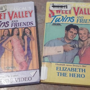 May include: Two VHS tapes of Sweet Valley Twins books. The first tape features a group of four girls on a stage, with the text "Sweet Valley Twins and Friends. Lila's Music Video." The second tape features two people, a man and a woman, with the text "Sweet Valley Twins and Friends. Elizabeth saves Denny's life! Elizabeth the Hero."