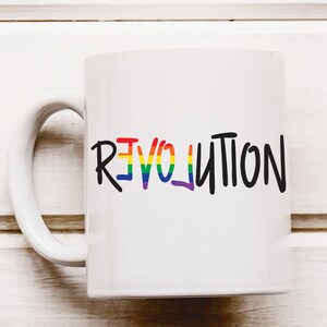 May include: White ceramic coffee mug with a rainbow-colored "REVOLUTION" graphic in black lettering.
