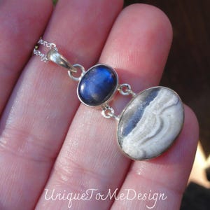 May include: A silver necklace with a blue oval labradorite gemstone and a white oval agate gemstone pendant. The pendant is attached to a silver chain.