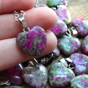 May include: A silver chain necklace with a heart-shaped pendant made of green and pink uvarovite gemstone. The pendant is approximately 2 cm in diameter.