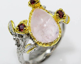 May include: A silver ring with a pink gemstone and three red gemstones set in gold. The ring features a delicate, branch-like design.