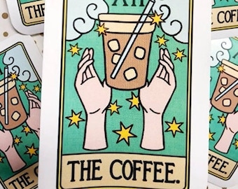May include: A tarot card with a green background and gold stars. The card is titled "The Coffee" and features a cartoon illustration of a coffee cup with a straw, held by two hands. The card number XII is displayed in the top center of the card.