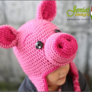 May include: Pink crocheted pig hat with a black button for an eye. The hat has a long snout and floppy ears.