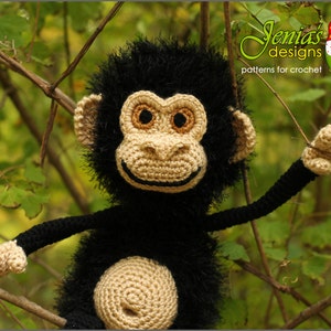 Peut inclure: Un singe en crochet avec une fourrure noire et un visage beige. Le jouet est assis sur une branche avec des feuilles vertes en arrière-plan.