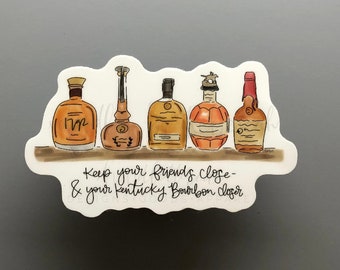May include: A sticker featuring five illustrated bourbon bottles in shades of brown and orange, arranged on a shelf. The text reads, "Keep your friends close & your Kentucky Bourbon closer."