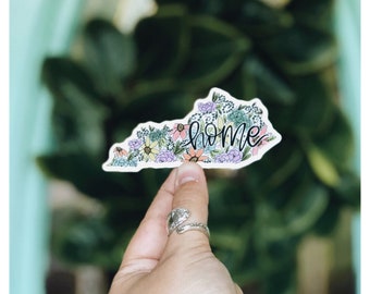Könnte beinhalten: Ein Aufkleber des Bundesstaates Kentucky mit einem floralen Design und dem Wort "home" in Kursivschrift.