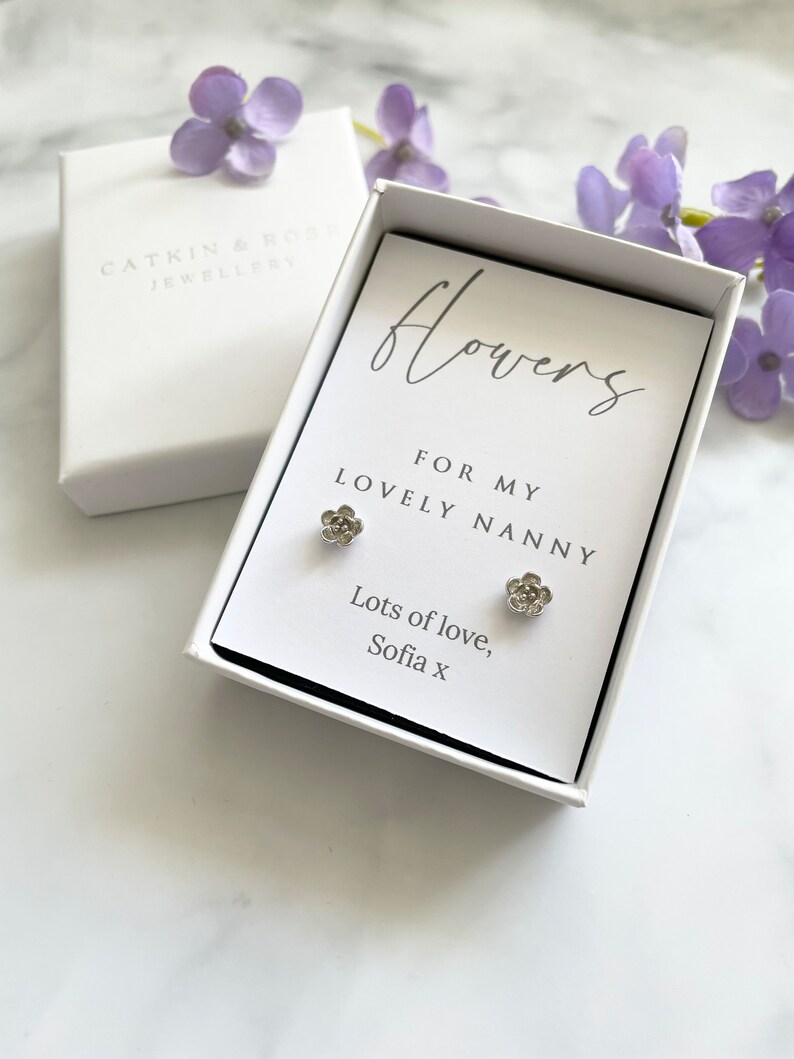 May include: A white gift box with a card that reads "flowers for my lovely nanny" and "lots of love, Sofia x". The card is decorated with two small silver flower earrings.