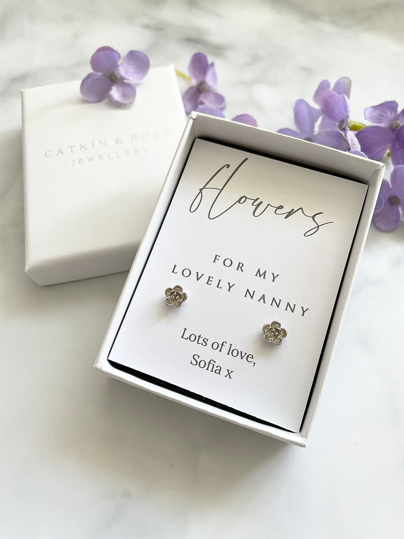 May include: A white gift box with a card that reads "flowers for my lovely nanny, lots of love, Sofia x". The card is decorated with two silver flower earrings.