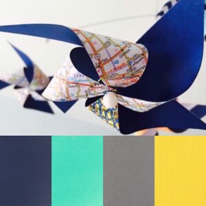 May include: A blue and white pinwheel with a map design. The pinwheel is hanging from the ceiling. The colours in the image are navy blue, turquoise, grey, and yellow.