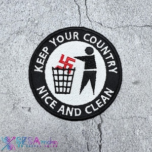 May include: Embroidered patch with a black border and white center. The patch features a stick figure throwing a red swastika into a trash can. The text "KEEP YOUR COUNTRY NICE AND CLEAN" is in a circular pattern.