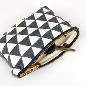 May include: A small zippered pouch with a white and gray geometric pattern. The pouch is open and a key is inside.