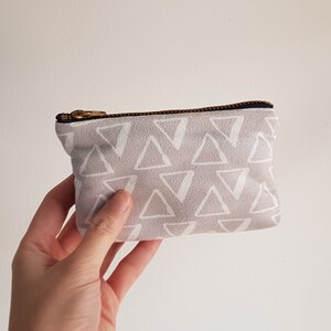 May include: A small gray zippered pouch with a white triangle pattern.