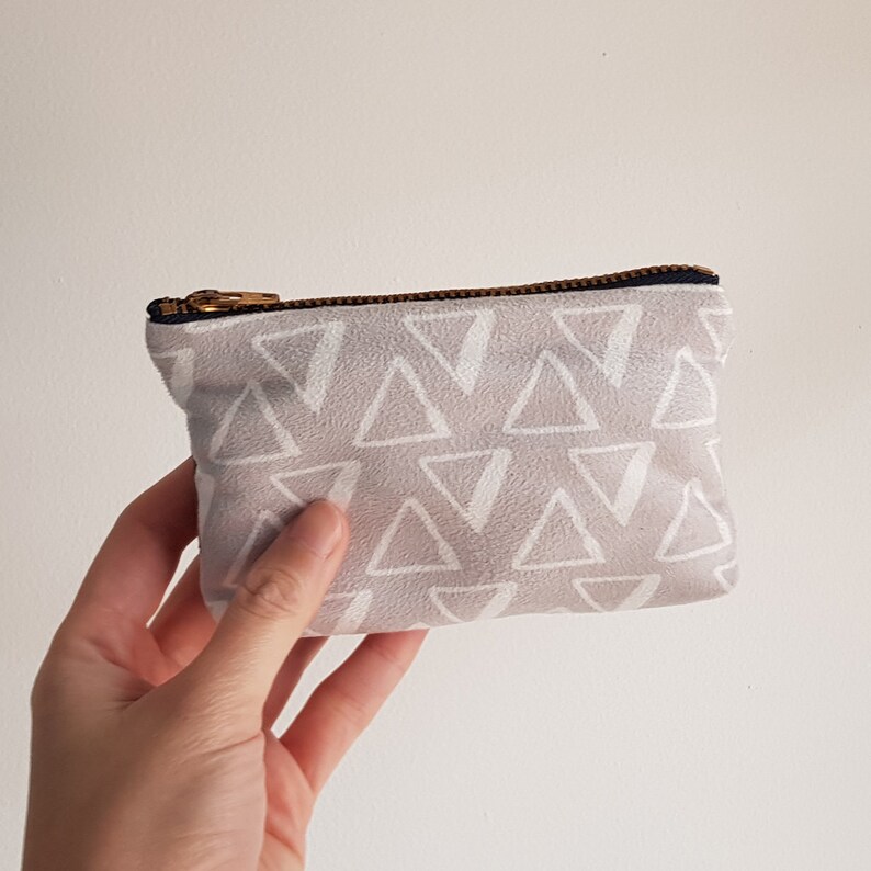 May include: A small gray zippered pouch with a white triangle pattern.