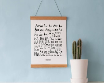May include: A black and white print with the word "laughter" repeated in various fonts and sizes. The print is framed with a light brown wood frame and is hanging on a light blue wall.