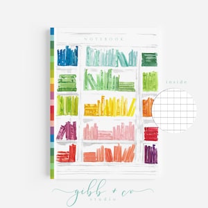 May include: A white notebook with a colorful illustration of a bookshelf filled with books. The notebook cover features the text "NOTEBOOK" and the text "inside" with a small grid pattern. The notebook is from the brand "gibb + co studio".