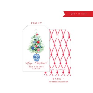 May include: A Christmas gift tag featuring a watercolour illustration of a Christmas tree in a blue and white planter. The tag has the text "Merry Christmas!" and "The Roberts Family" printed on it. The reverse of the tag has a pink and white pattern.