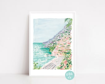 May include: Watercolour print of a coastal town with buildings on a hillside overlooking the turquoise sea. The artwork is framed in white and features the text "gibb + co" in a circular design.