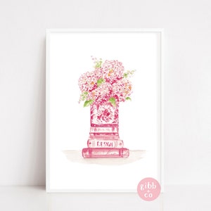 Peut inclure: Une peinture à l'aquarelle d'un arrangement floral rose dans un vase rose et blanc, posé sur une pile de livres roses. Les livres portent l'inscription "DESIGN" sur le dos.