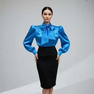 May include: A bright blue satin blouse featuring long puff sleeves, a high neckline with a large integrated bow tie, and buttoned cuffs, paired with a solid black knee-length pencil skirt that has a straight hemline and a fitted silhouette.