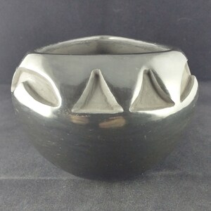 May include: Black pottery bowl with a geometric design. The bowl is made of black clay and has a smooth, glossy finish.