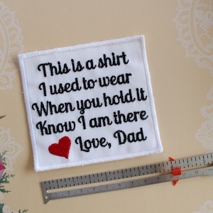 May include: White fabric patch with black embroidered text that reads "This is a shirt I used to wear When you hold it Know I am there Love, Dad". A red heart is embroidered below the text.