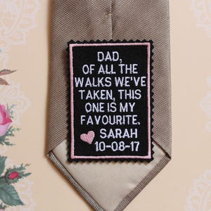 Könnte beinhalten: Ein gestickter schwarzer und weißer Aufnäher mit rosa Akzenten. Der Aufnäher trägt den Text "Papa, von all den Spaziergängen, die wir gemacht haben, ist dieser mein Lieblings. Sarah 10-08-17".