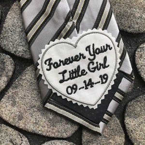 Peut inclure: Une cravate rayée grise et noire avec un patch blanc en forme de cœur qui dit "Forever Your Little Girl 09-14-19".
