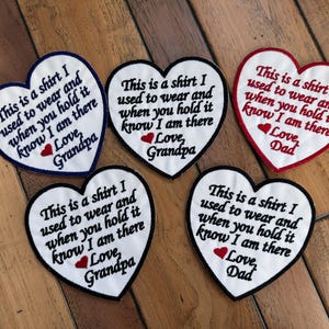 Peut inclure: Écussons en forme de cœur avec broderie. Les patchs blancs ont des bordures noires, rouges ou bleues. Le texte brodé dit : « This is a shirt I used to wear and when you hold it know I am there » avec « Love, Grandpa » ou « Love, Dad ».
