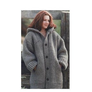 Könnte beinhalten: Ein grauer Kapuzenpullover mit Knöpfen. Der Pullover ist aus dickem, gestricktem Stoff und hat eine lockere Passform.