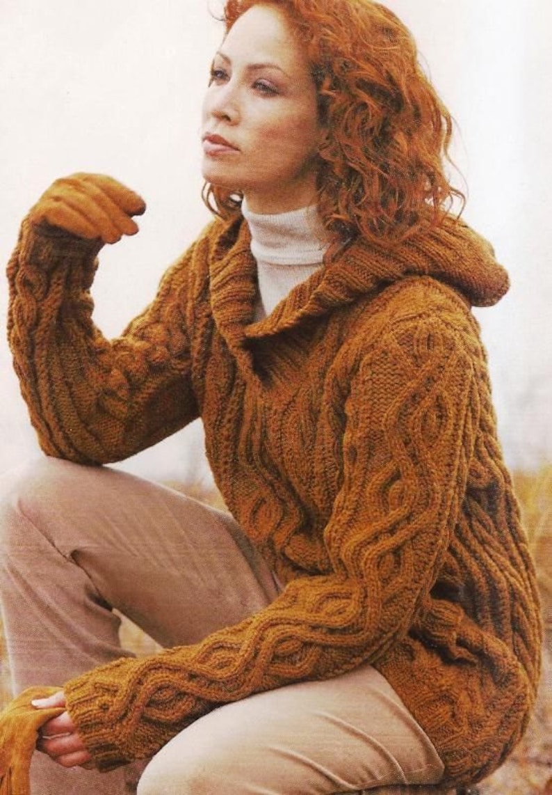 May include: A brown cable knit hooded sweater with a turtleneck collar. The sweater is made of a soft, warm yarn and has a relaxed fit.