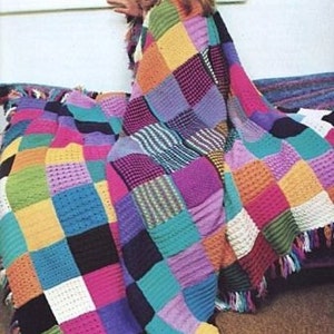 Puede incluir: Una colorida manta de ganchillo patchwork con una variedad de texturas y tonos, incluyendo rosa, morado, azul, naranja y verde. La manta tiene un borde con flecos y está sobre una persona. Un artículo hecho a mano y acogedor.