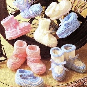 May include: A collection of knitted baby booties in pink, blue, and white. The booties are decorated with bows and are displayed on a wooden wheel.