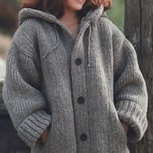 May include: A grey hooded cardigan sweater with a button fastening. The sweater is made from a thick, knitted fabric and has a relaxed fit.