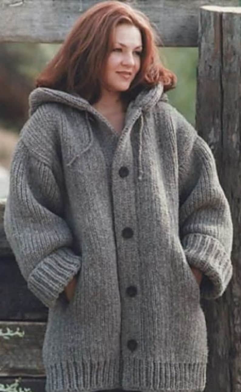 May include: A grey hooded cardigan sweater with a button fastening. The sweater is made from a thick, knitted fabric and has a relaxed fit.