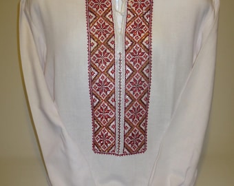 May include: A white long-sleeved shirt with red, gold, and white embroidered details on the collar and cuffs.