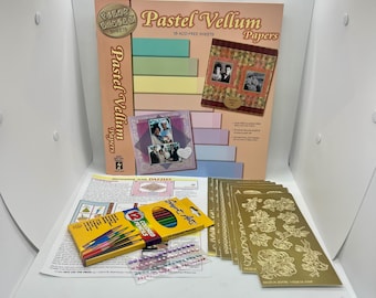 May include: A craft kit featuring a package of Pastel Vellum Papers, a box of 12 colored pencils, a sheet of adhesive pearls, and several gold-toned decorative sticker sheets with floral patterns, all displayed on a white surface.