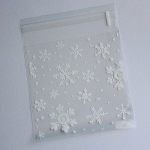 Puede incluir: Bolsa de pl&aacute;stico transparente con cierre resellable, decorada con copos de nieve blancos en relieve de varios tama&ntilde;os. La bolsa est&aacute; dise&ntilde;ada para art&iacute;culos peque&ntilde;os y tiene una est&eacute;tica sencilla y limpia, perfecta para regalos o embalajes de invierno.