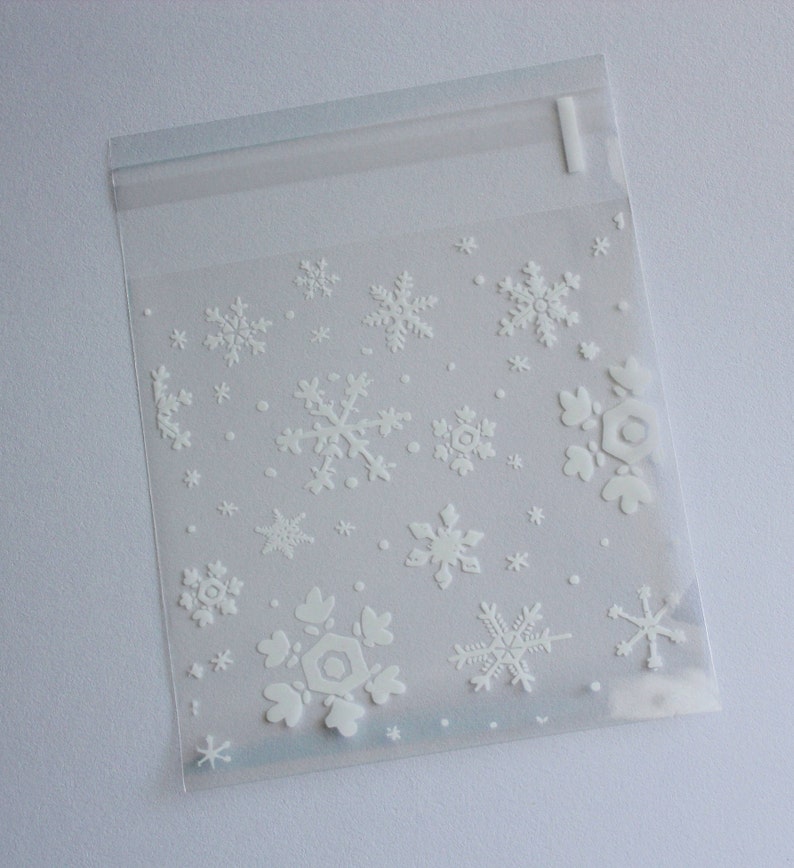 Puede incluir: Bolsa de pl&aacute;stico transparente con cierre resellable, decorada con copos de nieve blancos en relieve de varios tama&ntilde;os. La bolsa est&aacute; dise&ntilde;ada para art&iacute;culos peque&ntilde;os y tiene una est&eacute;tica sencilla y limpia, perfecta para regalos o embalajes de invierno.