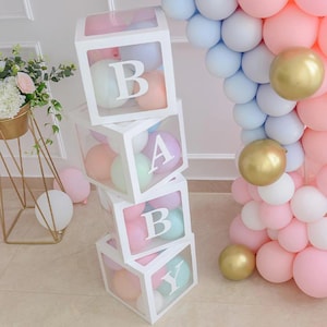 May include: A stack of four clear acrylic boxes with white frames, each containing pastel colored balloons. The boxes are stacked to spell out the word "BABY".